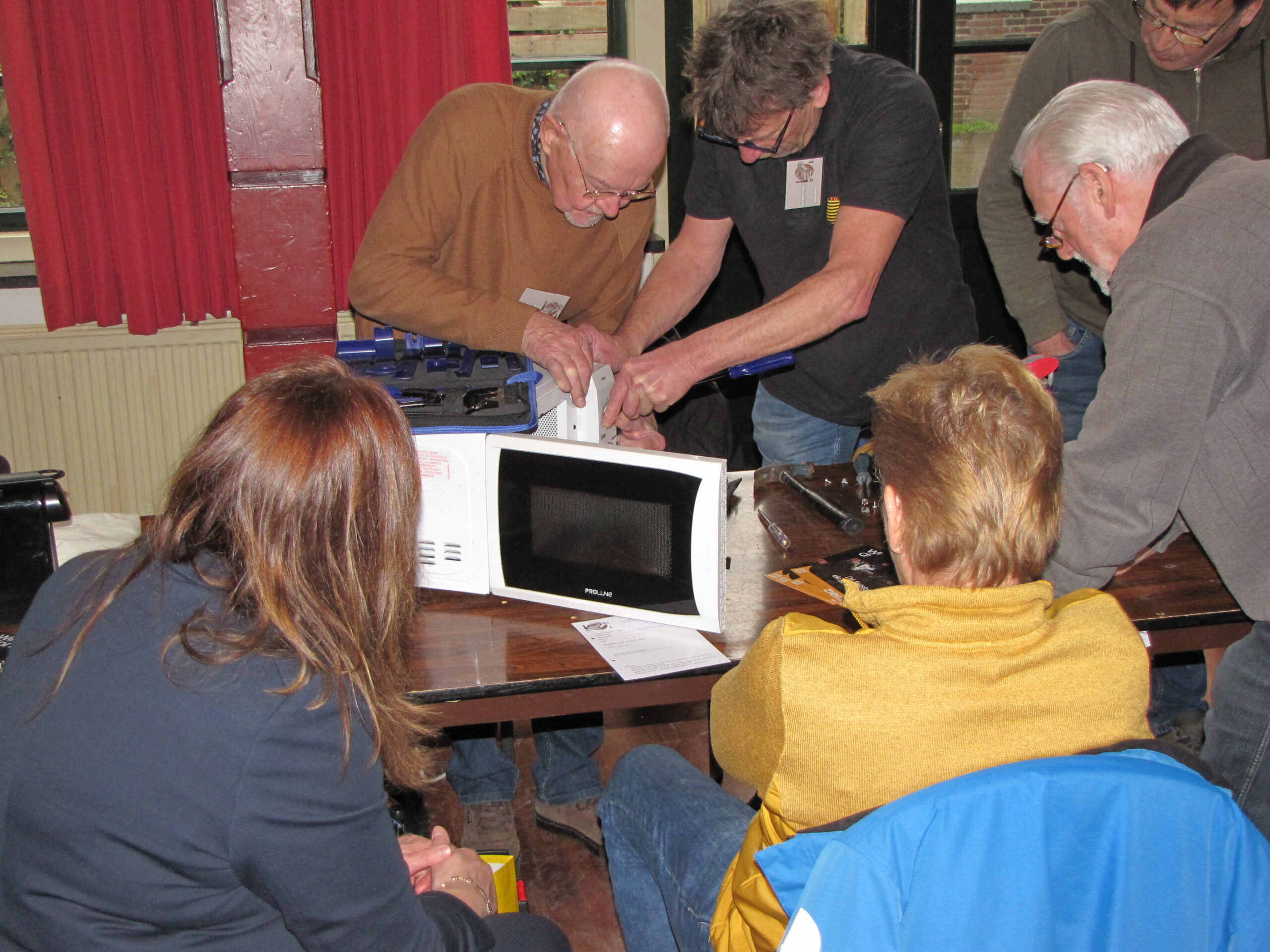Met vereende krachten wordt er gewerkt aan een magnetron. Met rechts, in het donkere shirt, Cees Loos. (Foto: Paul Aalbers)