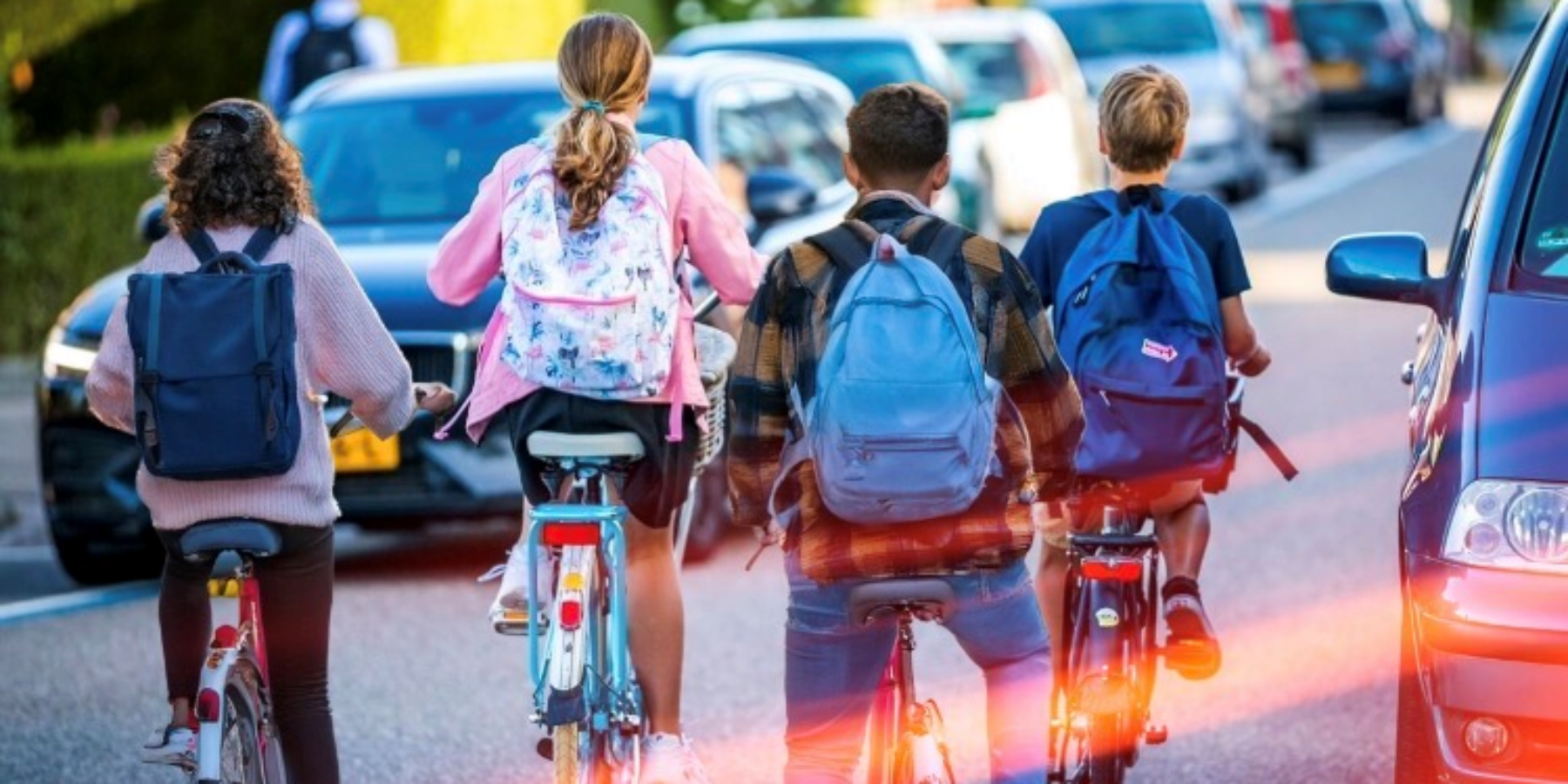 Fietsende kinderen met rugtassen op straat.