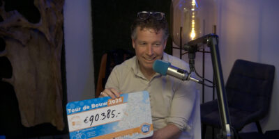 Martijn Houwaard houdt een cheque omhoog ter waarde van 90.385 euro. Dit is de opbrengst van de Tour de Bouw in 2025