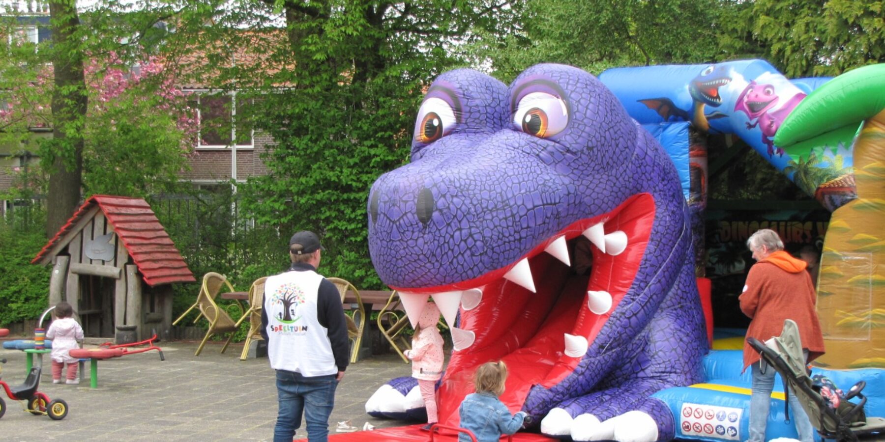 Een grote paarse opblaasdraak in een speeltuin.