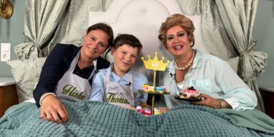 Thomas, Hiske en Christine Carrington liggen in bed en poseren voor de camera met de beker die Thomas won tijdens Heel Holland Bakt Kids.