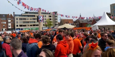 Een feestplein op Koningsdag in Leiden met veel mensen die gekleed zijn in oranje.