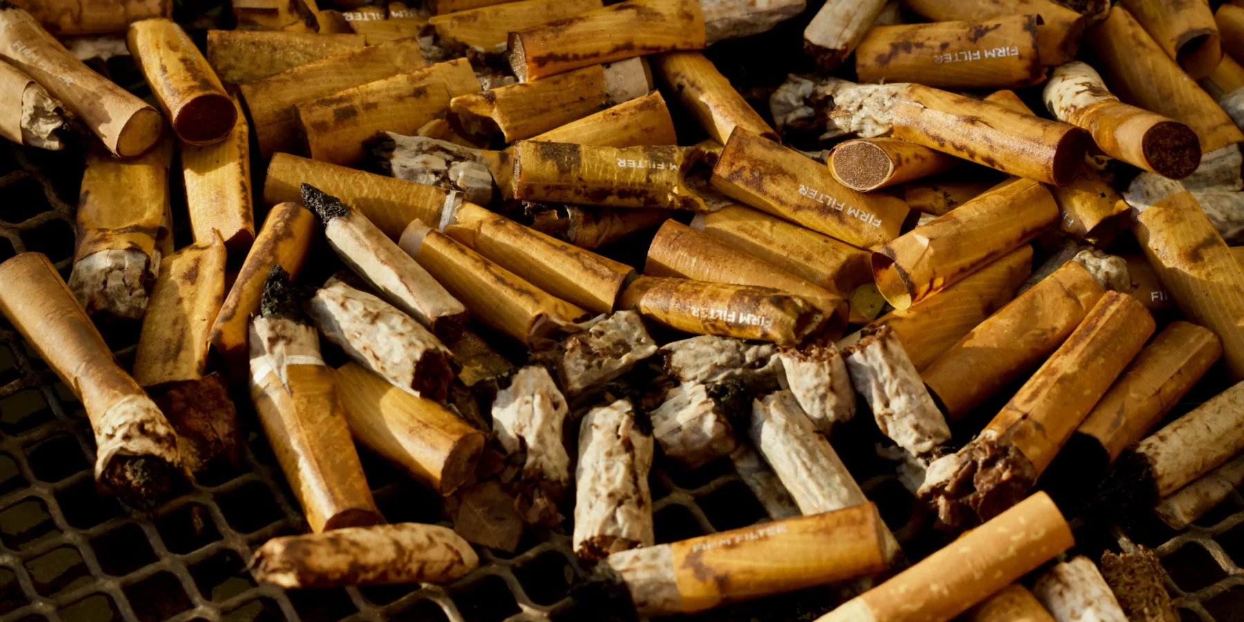 Een verzameling sigarettenfilters op een rooster