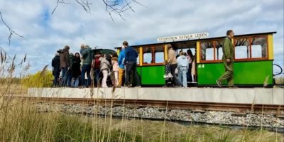 Mensen betreden de Stoomtrein Katwijk Leiden, die langs het Valkenburgse Meer rijdt.