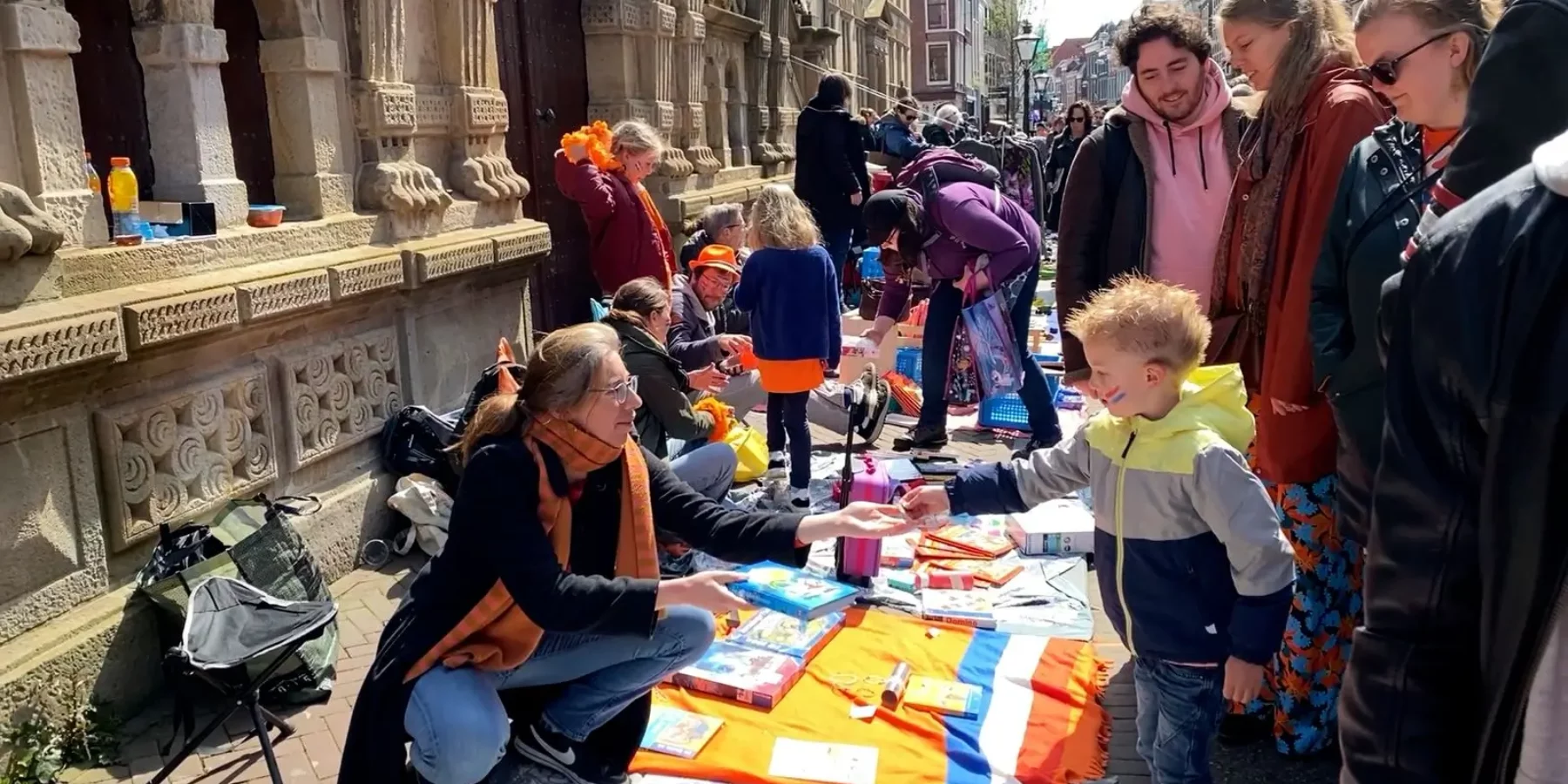 Een kind koopt iets op de vrijmarkt op Koningsdag in Leiden.