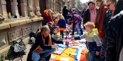 Een kind koopt iets op de vrijmarkt op Koningsdag in Leiden.