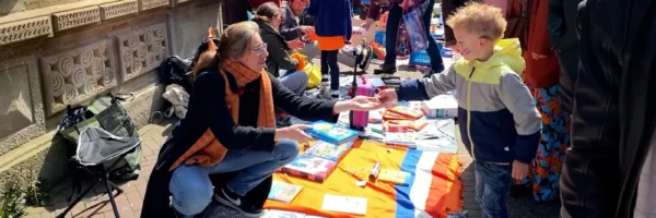 Een kind koopt iets op de vrijmarkt op Koningsdag in Leiden.