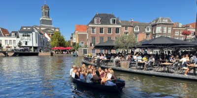 De aalmarkt in Leiden met een boot met studenten in het water een gezellig vol terras bij Annie's.