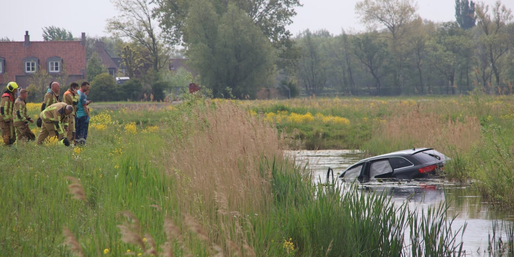 De auto in het water langs de Ruigelaan in Wassenaar. De hulpdiensten zijn ter plaatse.