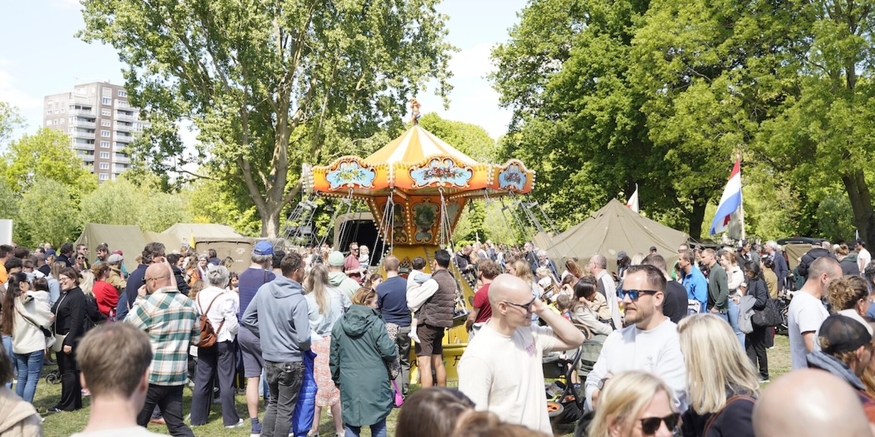 Park de Houtkamp in Leiderdorp met het bevrijdingsfestival. Op de foto staan publiek en een draaimolen.