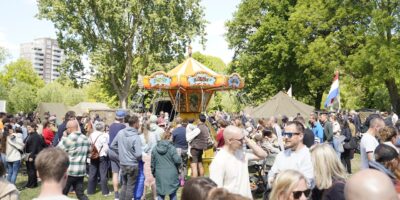 Park de Houtkamp in Leiderdorp met het bevrijdingsfestival. Op de foto staan publiek en een draaimolen.
