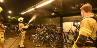 Fietsen in brand onder een overkapping bij Station de Vink in Voorschoten. De brandweer aan het blussen.