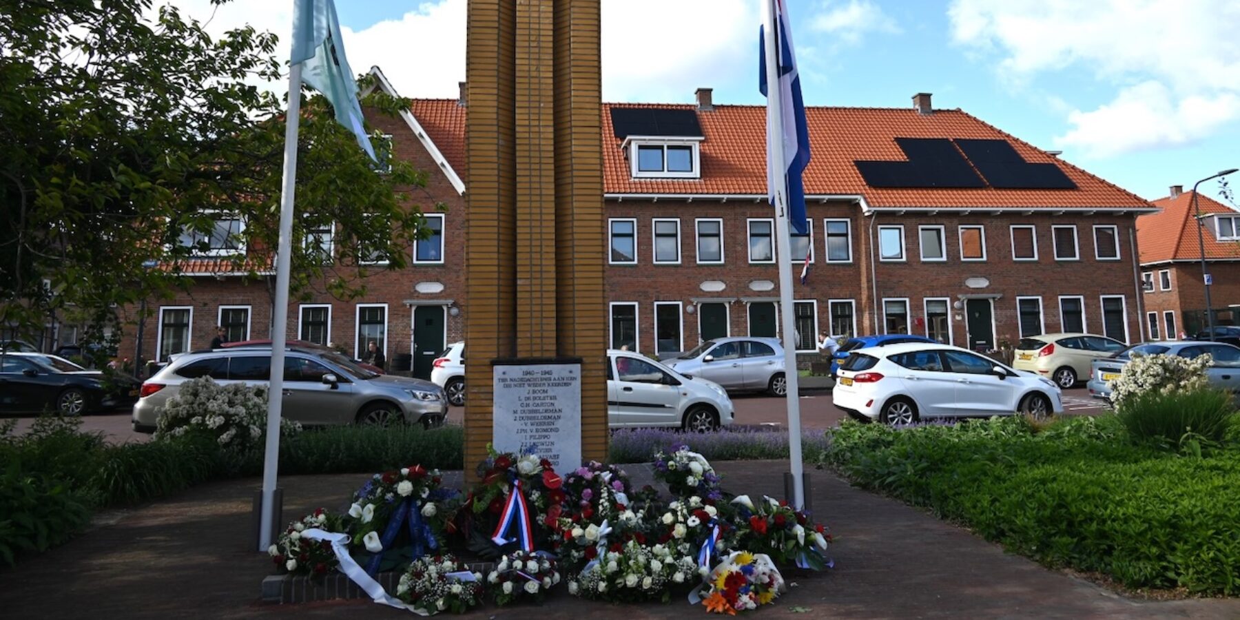 Herdenkinsmonument De Naald bij de Kooi in Leiden. Er staan vlaggen en liggen kransen en bloemen.