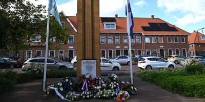 Herdenkinsmonument De Naald bij de Kooi in Leiden. Er staan vlaggen en liggen kransen en bloemen.