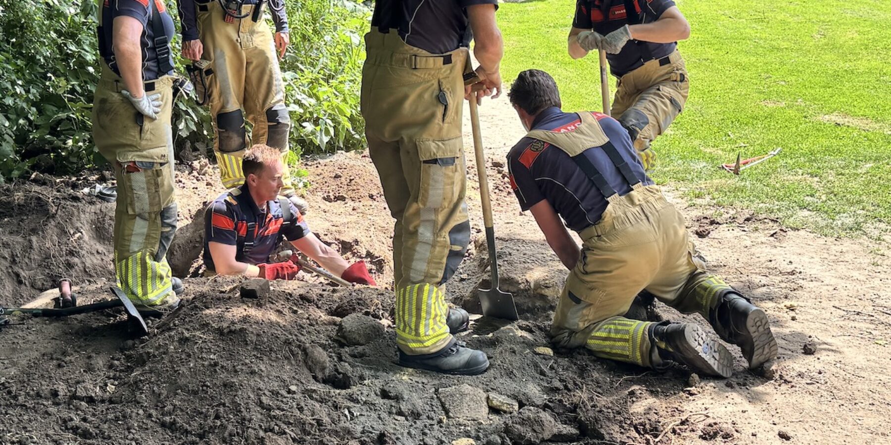 Brandweerlieden aan het graven in park De Houtkamp in Leiderdorp om een hond te bevrijden uit een tunnel.