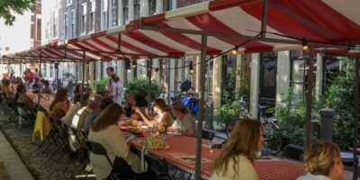 Bezoekers zitten aan lange tafels tijdens De Langste Leidse Tafel op de Hooglandse Kerkgracht in Leiden