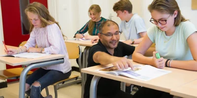 Kinderen in een klaslokaal van Winford College. Een leerling krijgt uitleg van de docent.