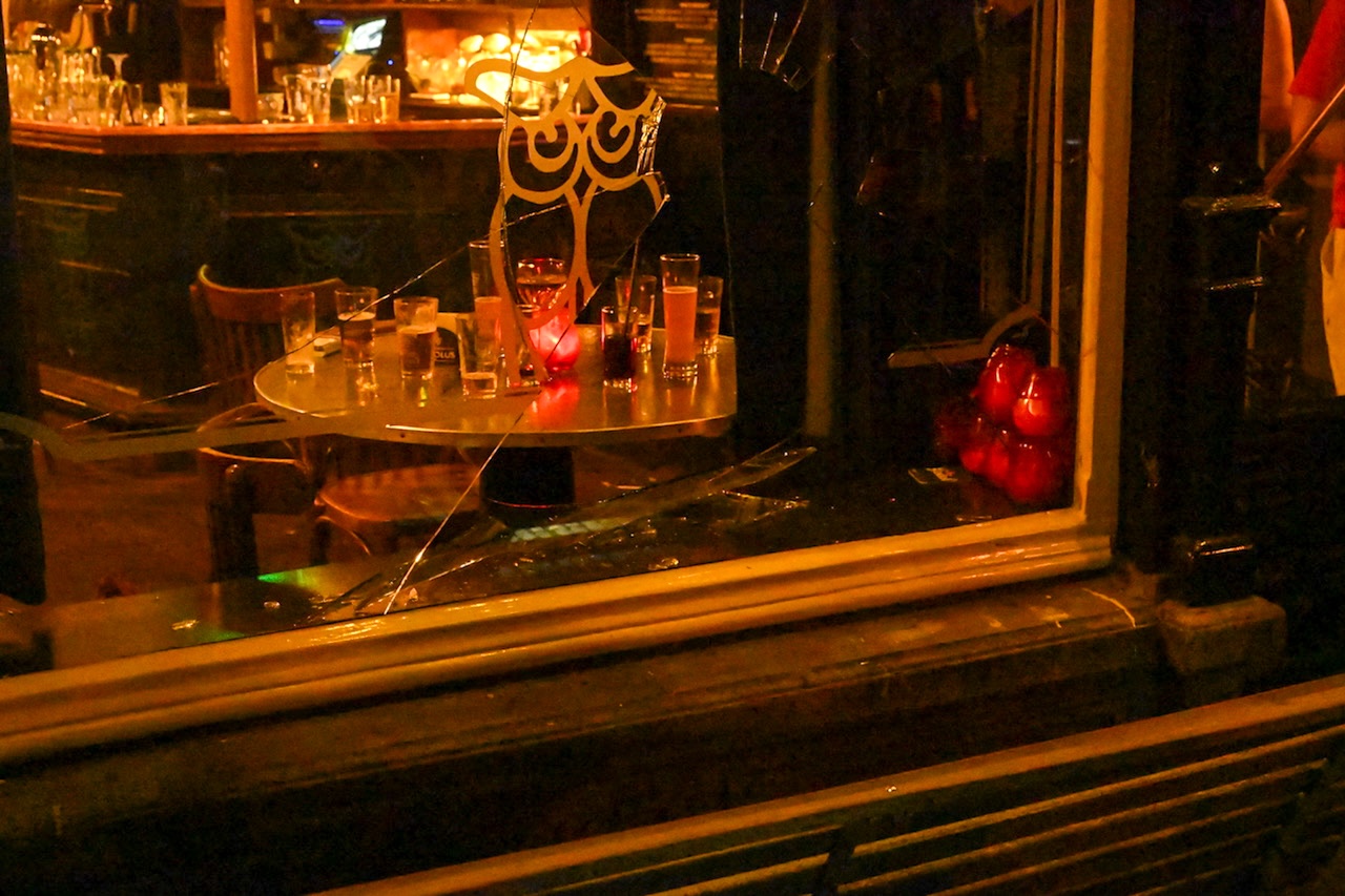 Een gat in de ruit van de gevel van Café de Uyl aan de Nieuwstraat in Leiden. Een man is door de ruit gevallen.