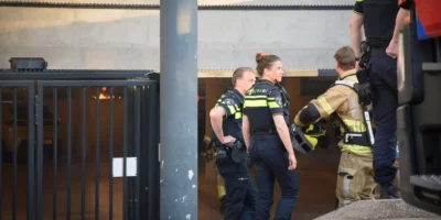 Twee politielieden en een brandweerlied bij de ingang van een parkeergarage aan het Bonaireplein. De garage stond in brand.