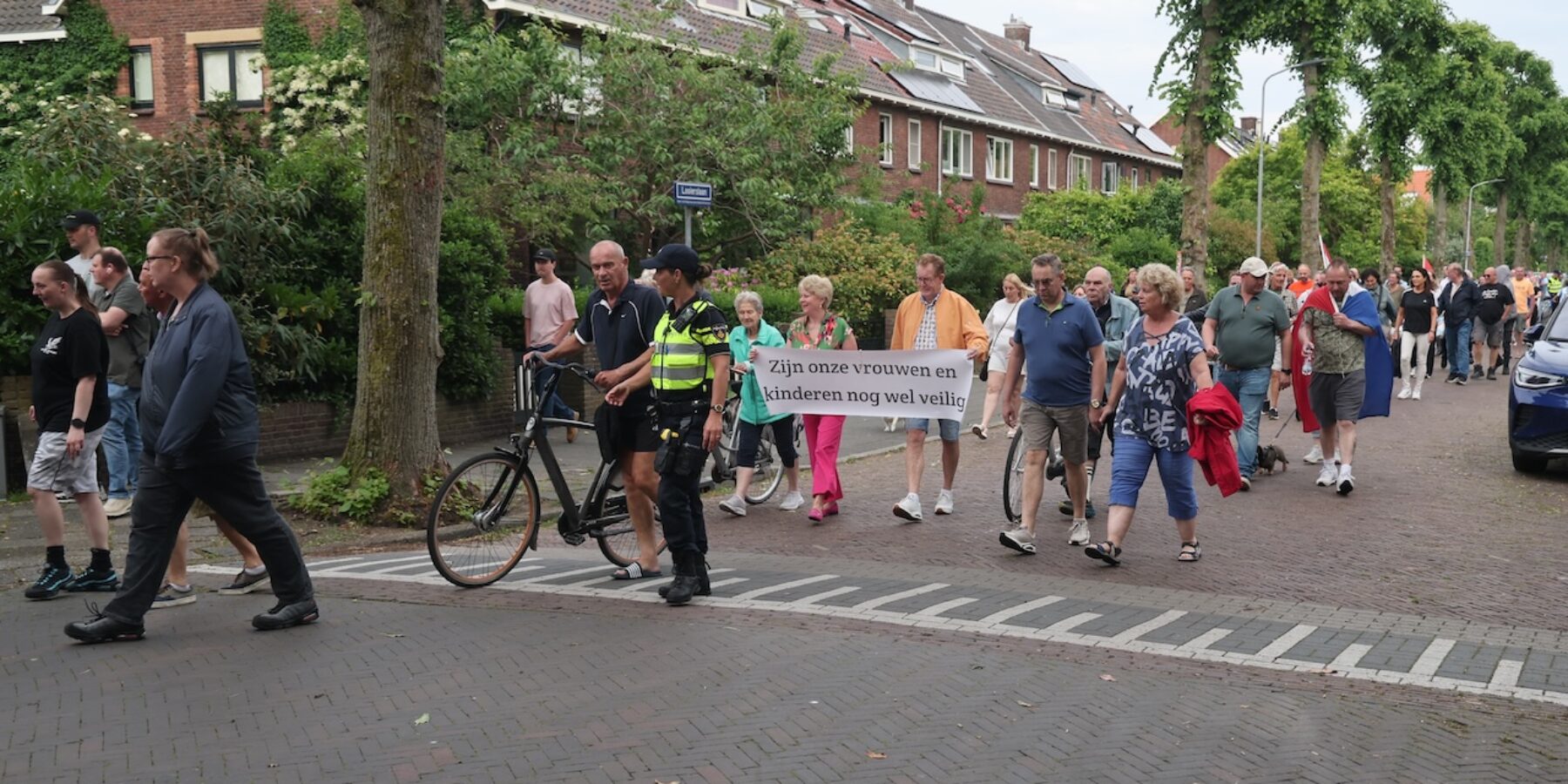 Groep demonstrerende mensen op straat in Leidschendam-Voorburg. Zichtbaar met een spandoek.