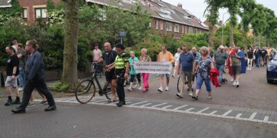 Groep demonstrerende mensen op straat in Leidschendam-Voorburg. Zichtbaar met een spandoek.