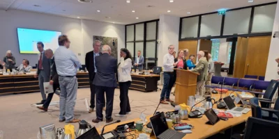 Raadsleden staan met elkaar te praten in de raadszaal van Oegstgeest tijdens een schorsing van de raadsvergadering.