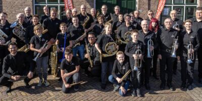 Op de foto is een groep mensen, gekleed in het zwart, te zien. Het zijn leden van de St Jan's Fanfare in Zoeterwoude.