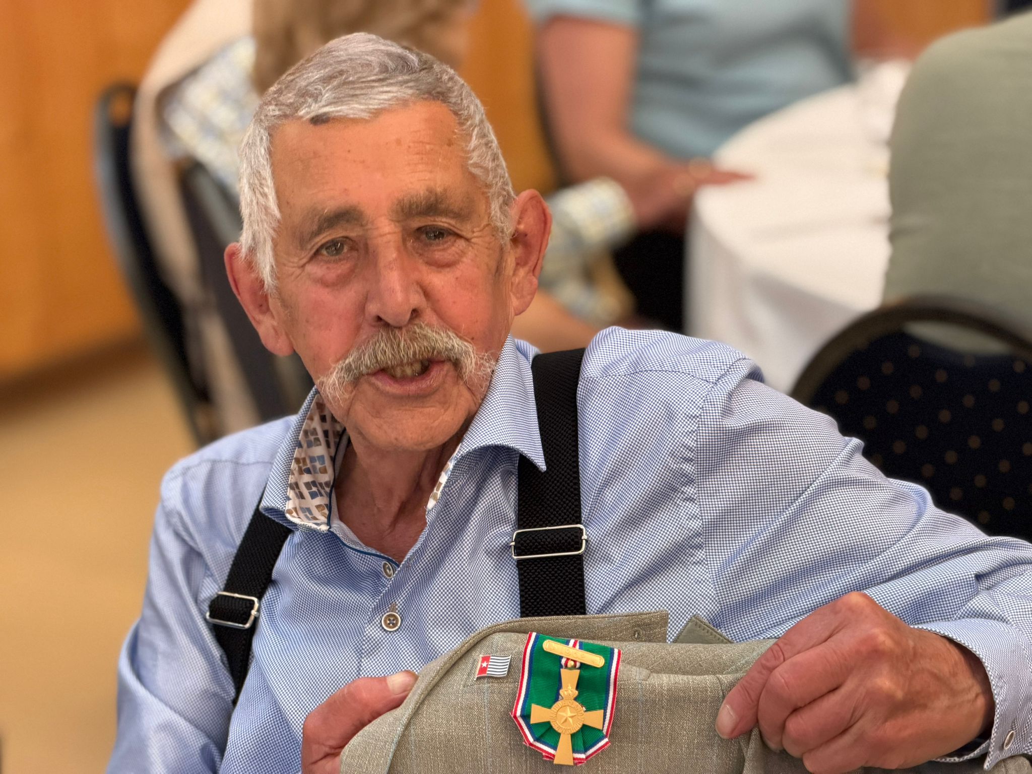 Een veteraan laat vol trots een badge zien.