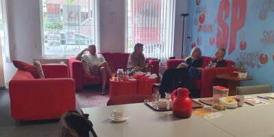 Mensen drinken koffie bij het gebouw van SP Leiden aan de Marnixstraat.