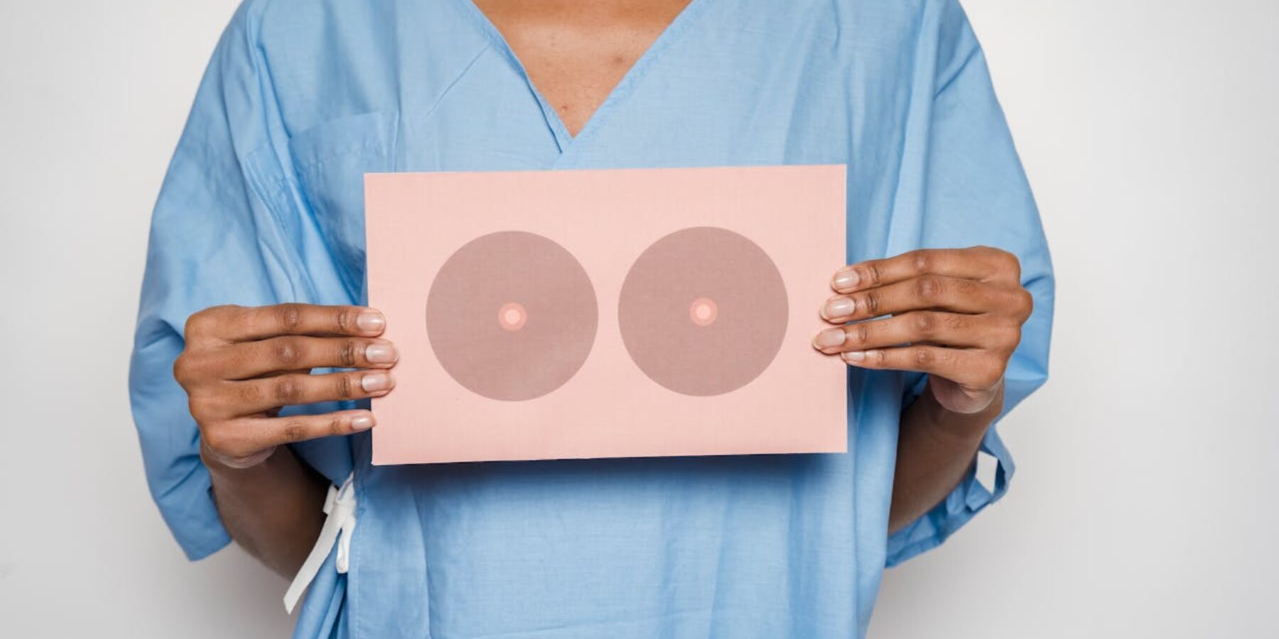 Een vrouw met een bordje met twee cirkels. In de twee cirkels zit een klein cirkeltje. Het symboliseert borsten.