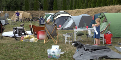 Buurtcamping in park Matilo. Op de foto staan tenten, campingstoeltjes en -tafeltjes en tassen.