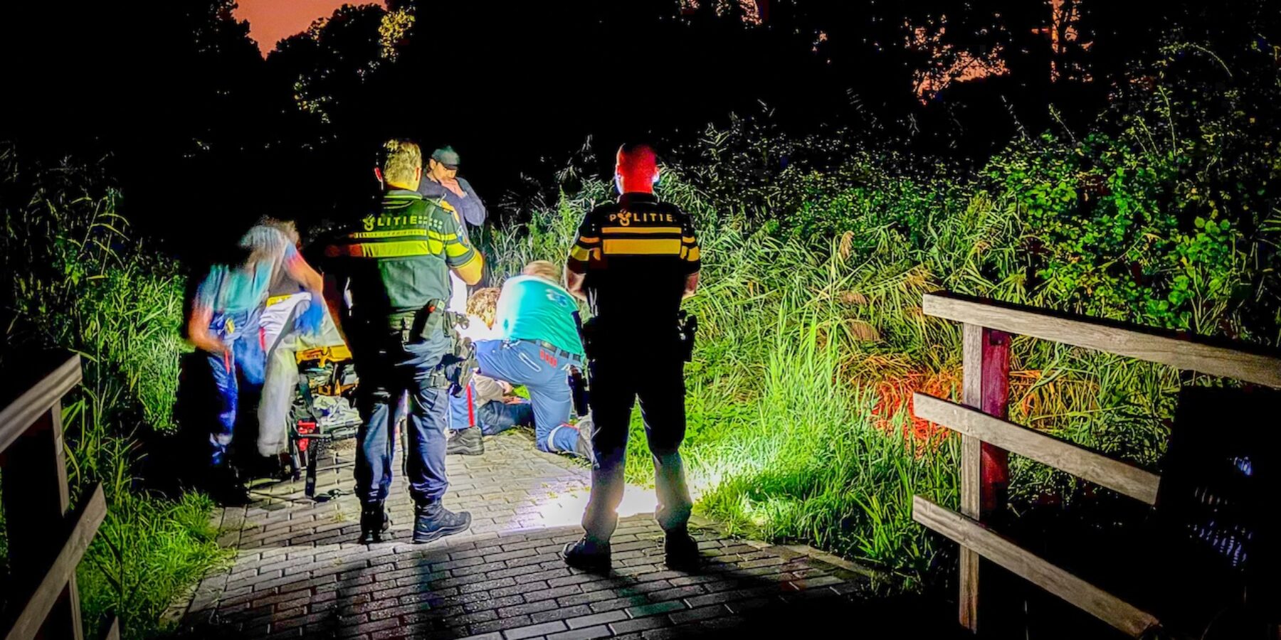 De hulpdiensten helpen de man die met zijn scootmobiel in het water terecht gekomen was.