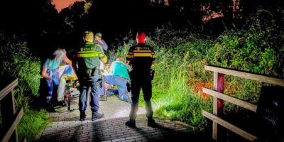 De hulpdiensten helpen de man die met zijn scootmobiel in het water terecht gekomen was.