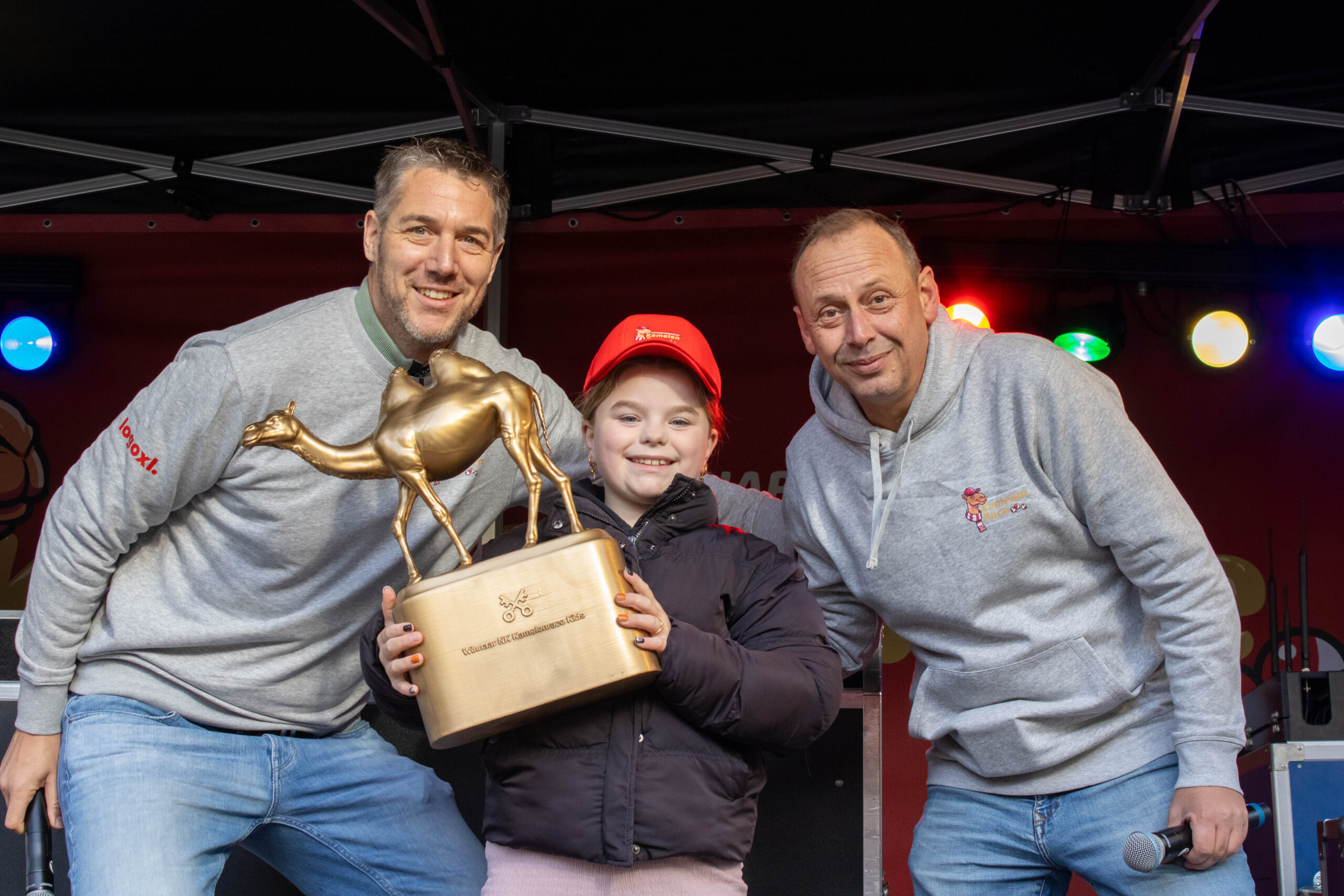 Bente Nauta, winnares bij de kinderen, met links presentator Joost van der Wal en rechts organisator en presentator Nikos van Aelst. (Foto: JW Creations)