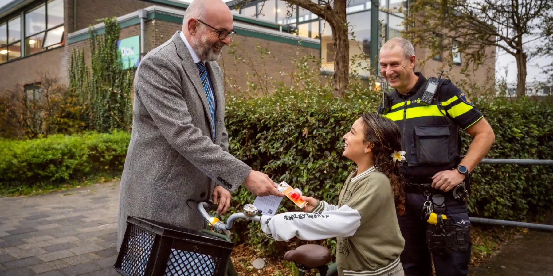 Leerling van basisschool De Driemaster ontvangt van fietslampjes van burgemeester Martijn Vroom in kader van campagne lichten AAN